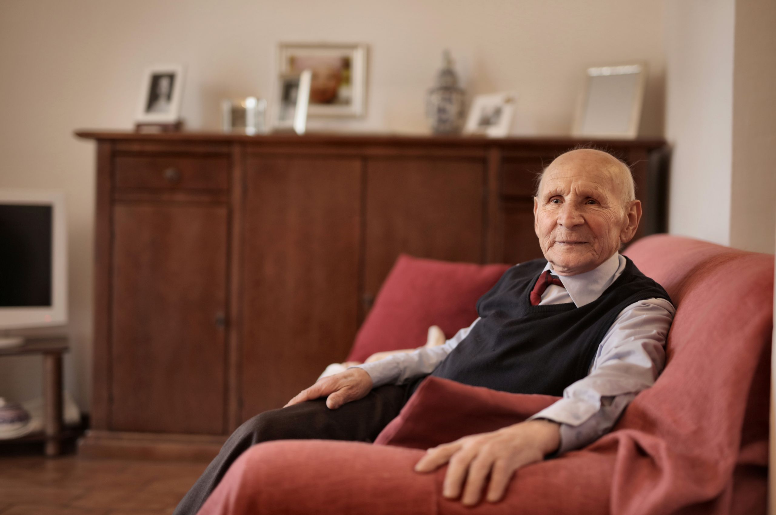 Senior man sitting comfortably on a sofa in a warm and inviting living room.
