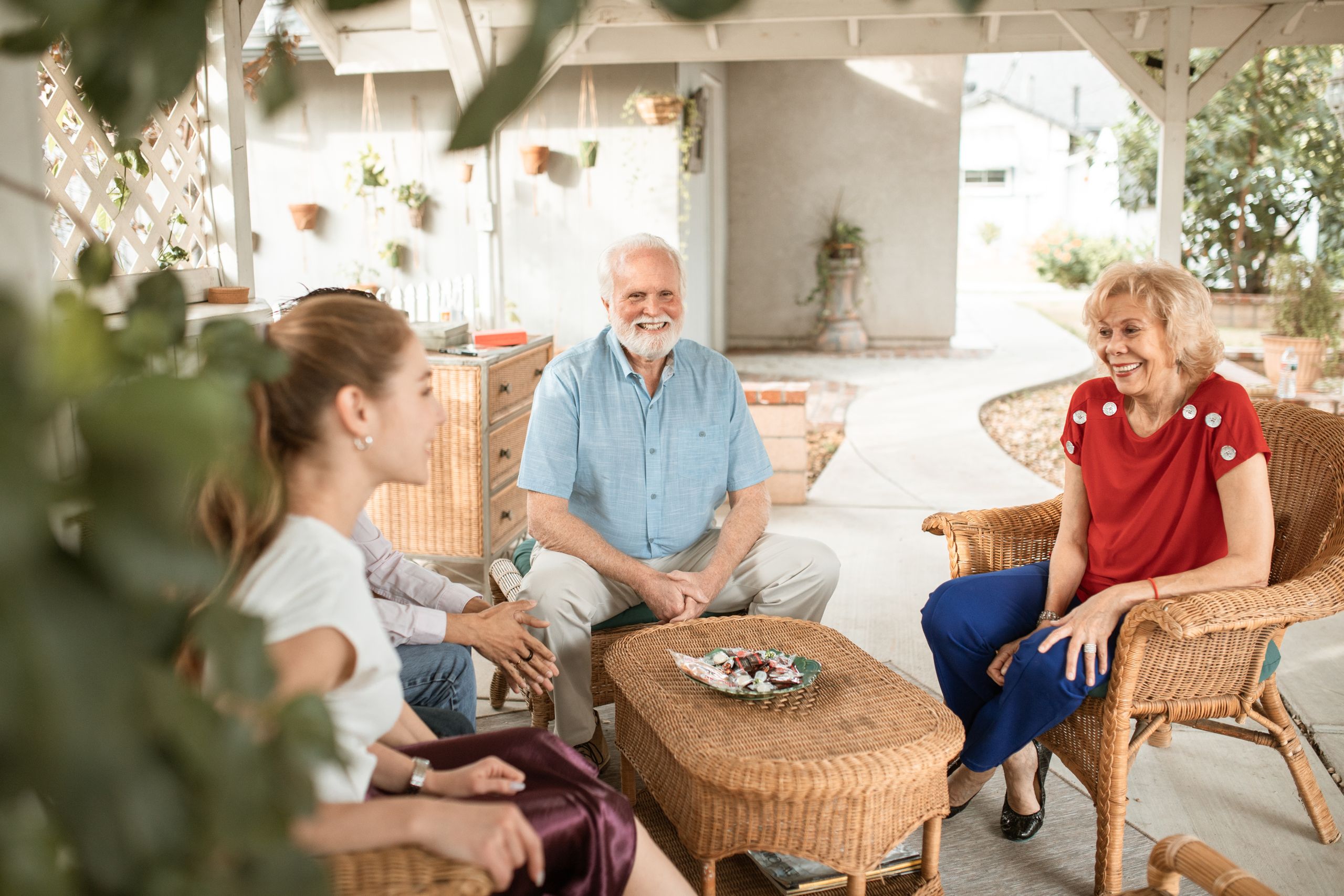 Family enjoying a relaxed conversation on a cozy outdoor patio with natural light.
